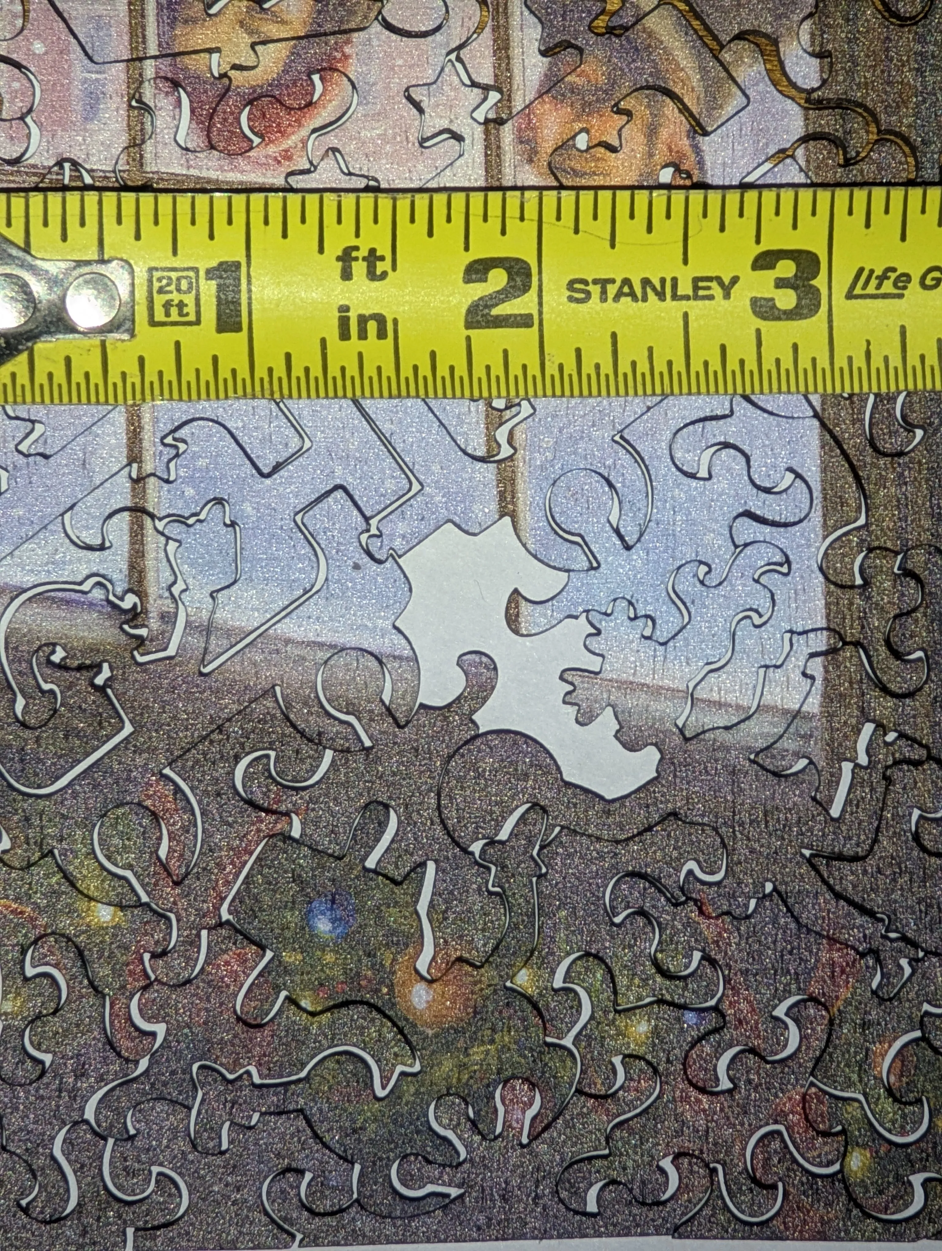 Top-down photo of the puzzle with a Stanley tape measure laid across it showing the empty piece slot